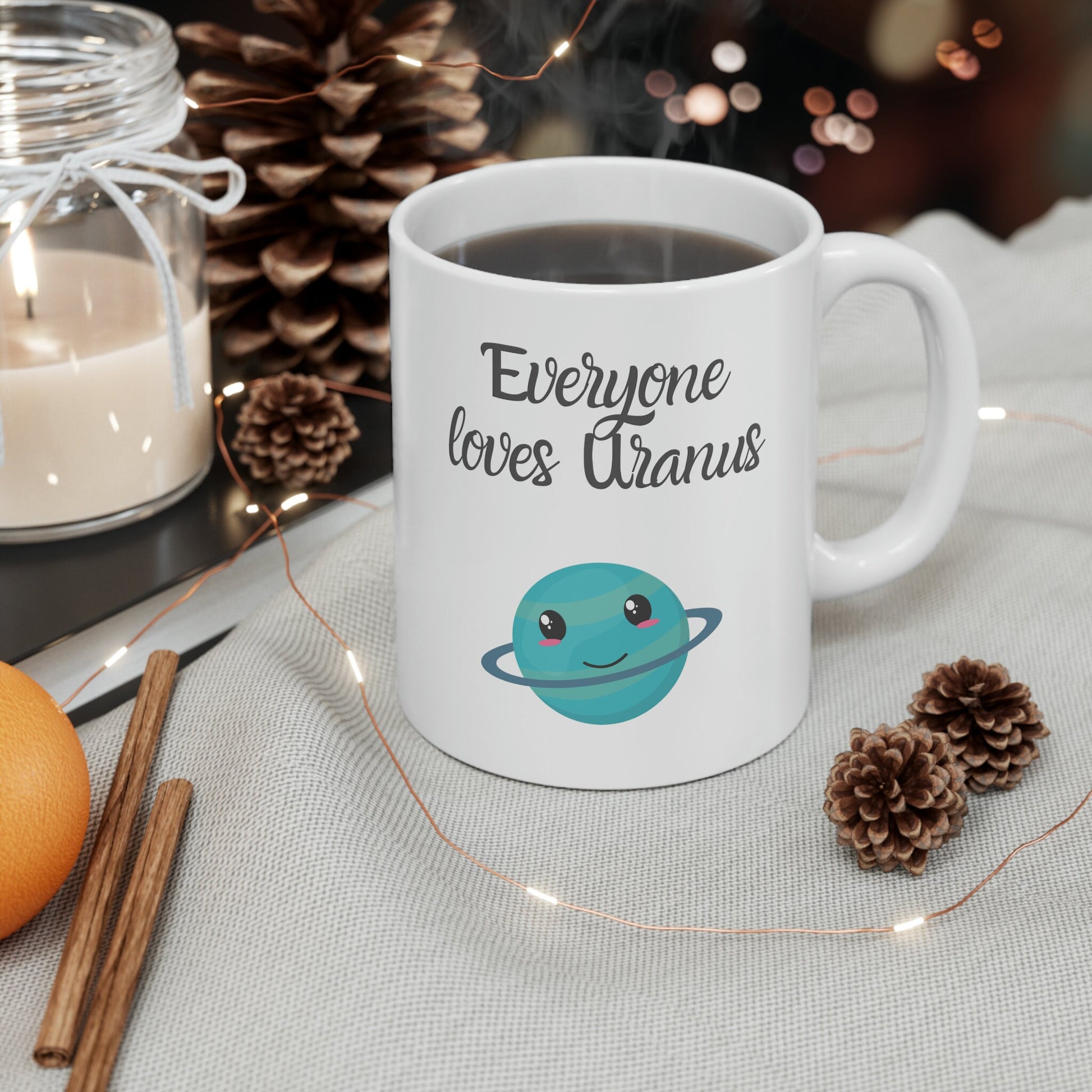 White Ceramic Mug with words in Script style black font that say, Everyone Loves Uranus. Beneath you find a Cute graphic of the Planet Uranus with an adorable face.  Check out the shop for more items at www.scorpiontees.etsy.com