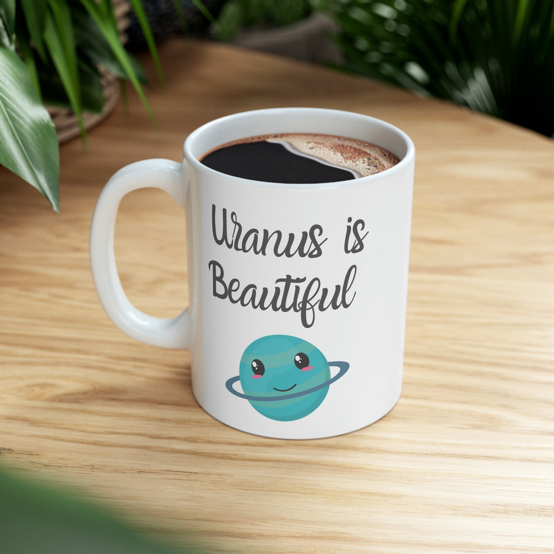 White Ceramic Mug with words in Script style black font that say, Uranus is Beautiful.  Beneath you find a Cute graphic of the Planet Uranus with an adorable face.  Check out the shop for more items at www.scorpiontees.etsy.com