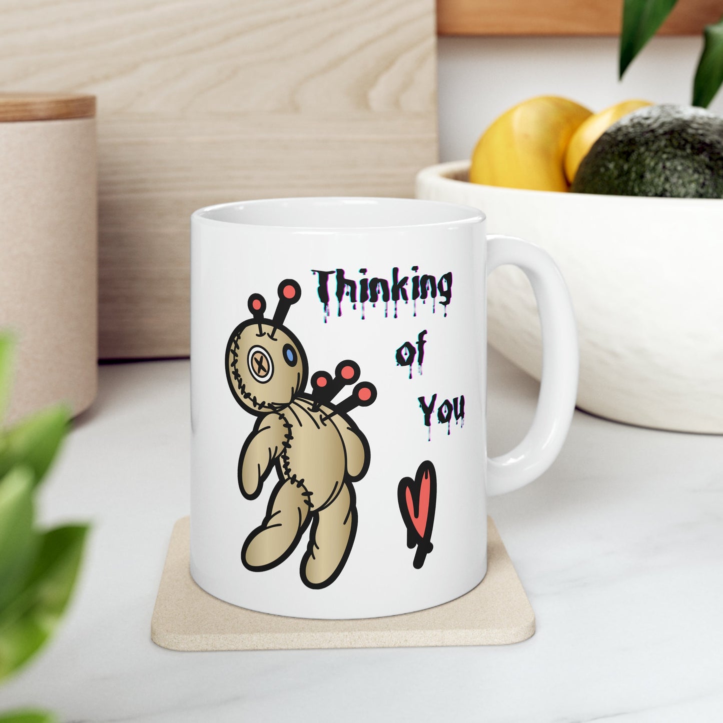 white ceramic coffee mug with a Voo doo doll being poked with pins.  The words Thinking of you are written in a scary dripping Halloween Font.  A red heart is under the wording.  Check out my shop at www.scorpiontees.etsy.com