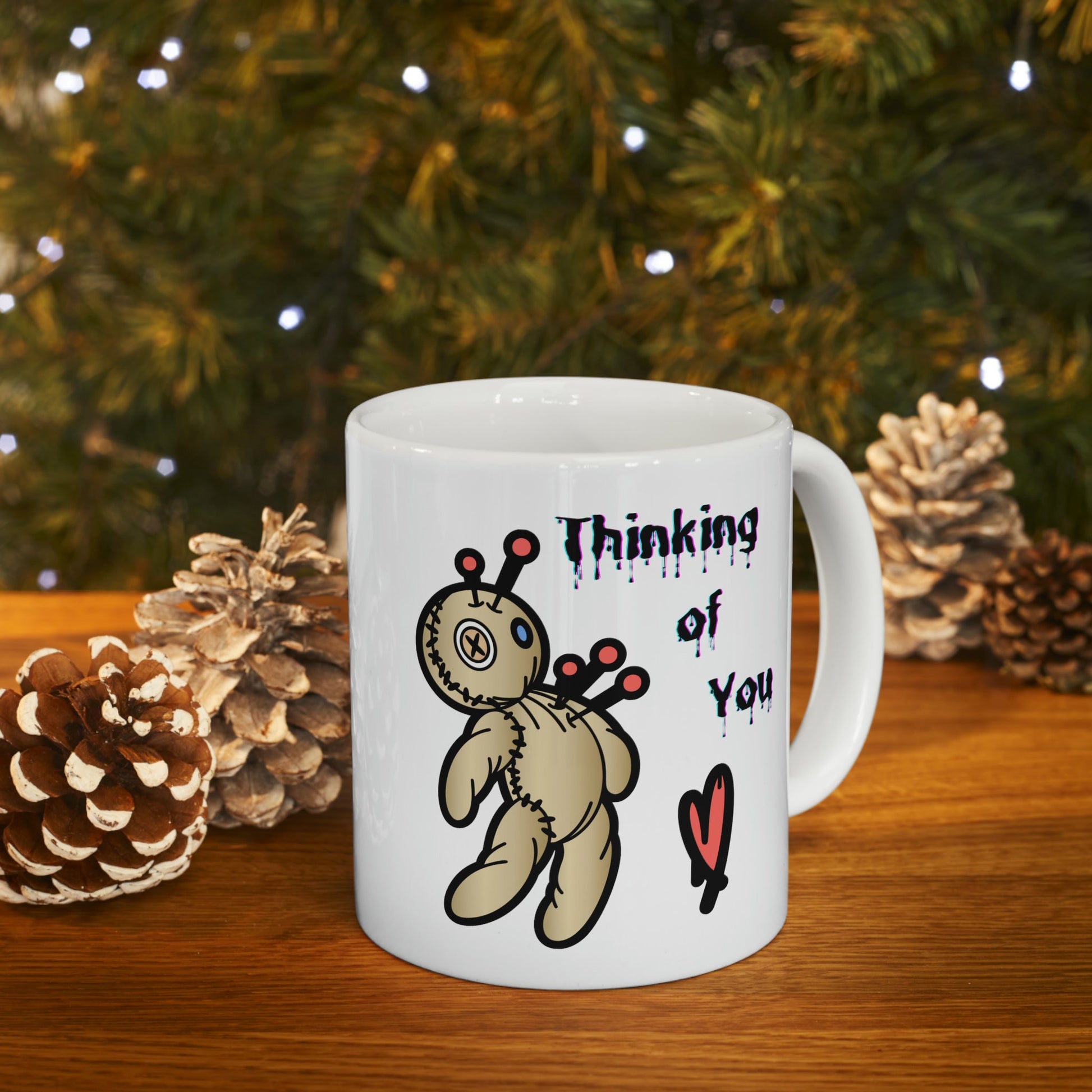 white ceramic coffee mug with a Voo doo doll being poked with pins.  The words Thinking of you are written in a scary dripping Halloween Font.  A red heart is under the wording.  Check out my shop at www.scorpiontees.etsy.com