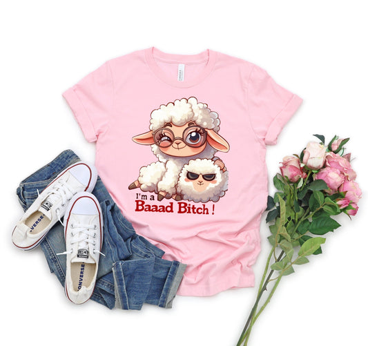 Pink T Shirt with a cute sheep wearing glasses and the words Im a baaad bitch in black and Red Letters.  The Sheep is holding a smaller sheep with black eyes that look like sunglasses. www.scorpiontees.etsy.com